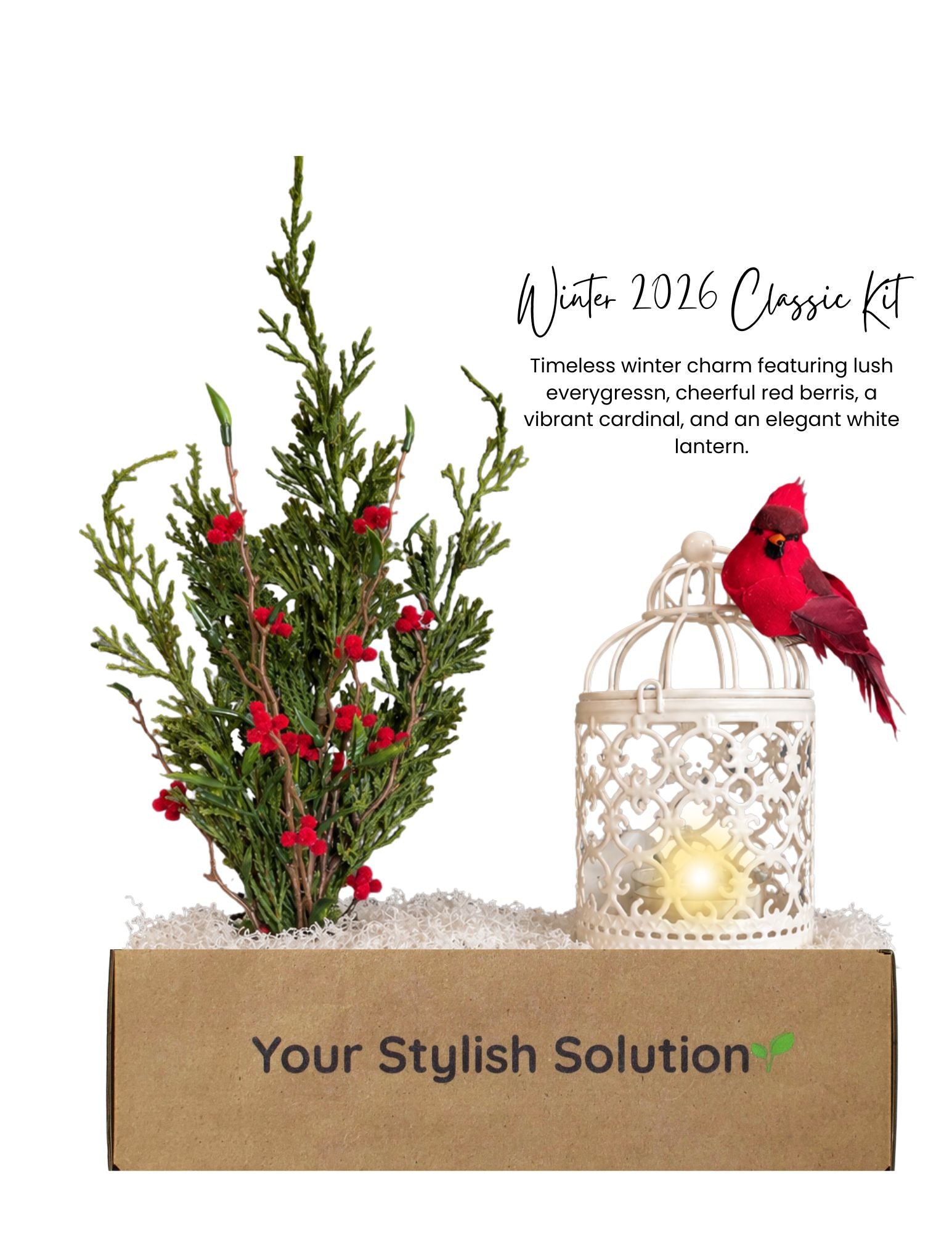 Winter 2026 Classic décor kit featuring lush evergreen branches, red berries, a vibrant red cardinal, and an elegant white lantern in a branded box.
