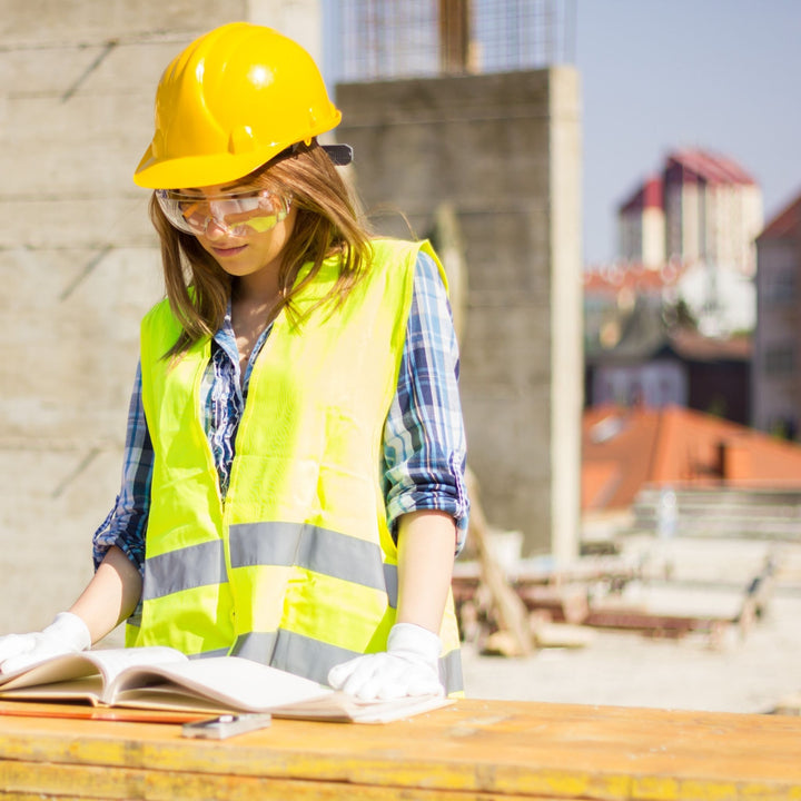 woman in construction field reading plans 